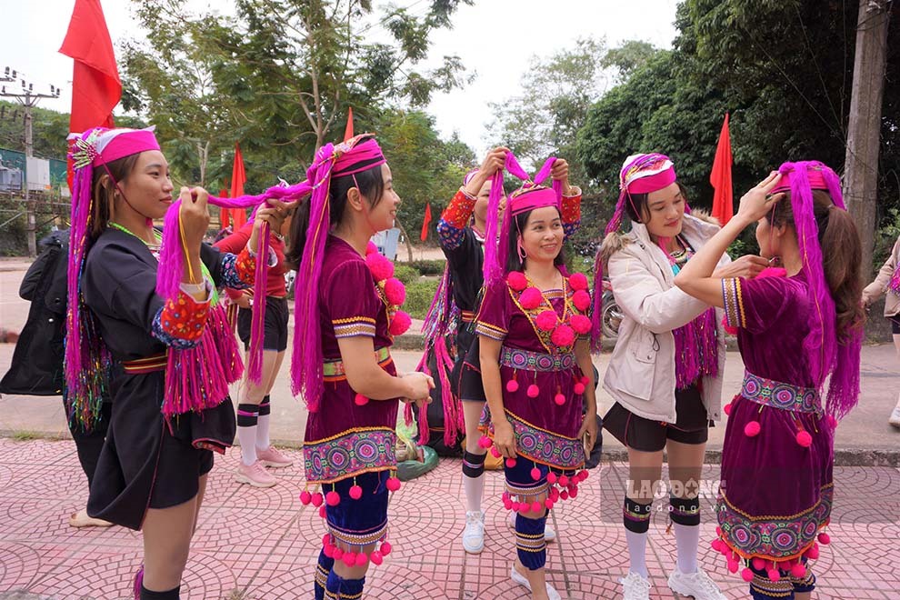 Phụ nữ Dao chỉnh sửa trang phục cho nhau trước giờ lễ hội diễn ra. Ảnh: Đoàn Hưng